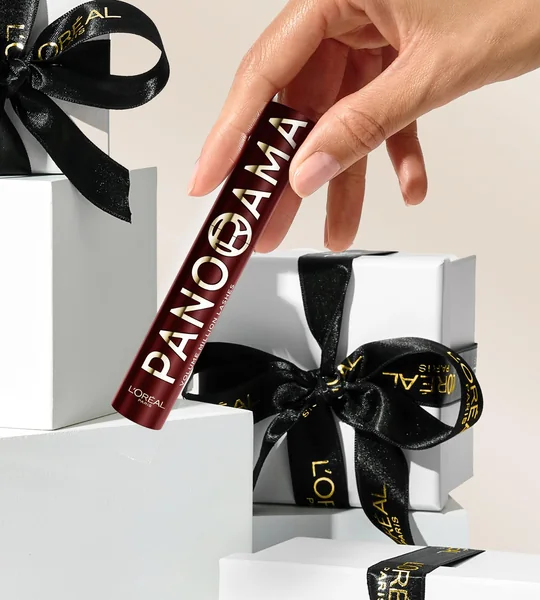 Main tenant le mascara Panorama devant des coffrets cadeaux